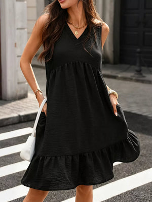 Black V-neck sleeveless dress with ruffle hem and pockets, styled with a white handbag.