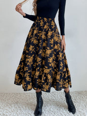 Tiered midi skirt with yellow floral print on black fabric, elastic waist, and ruffled hem.
