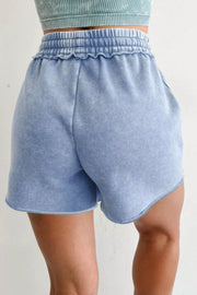 Blue cotton drawstring shorts with ruffled elastic waistband and raw hem.