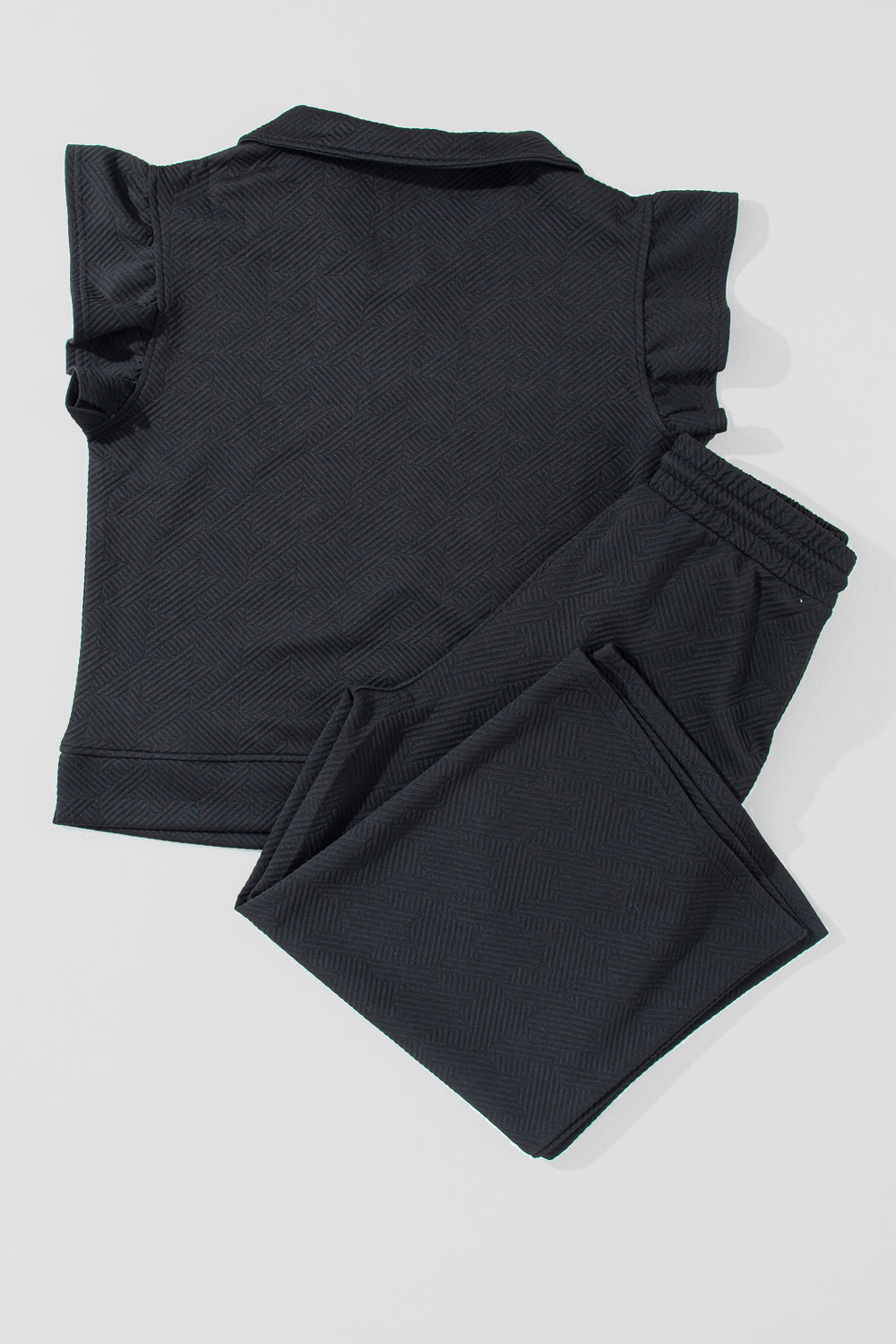 Black textured loungewear set with ruffle sleeve zip-up top and drawstring pants.