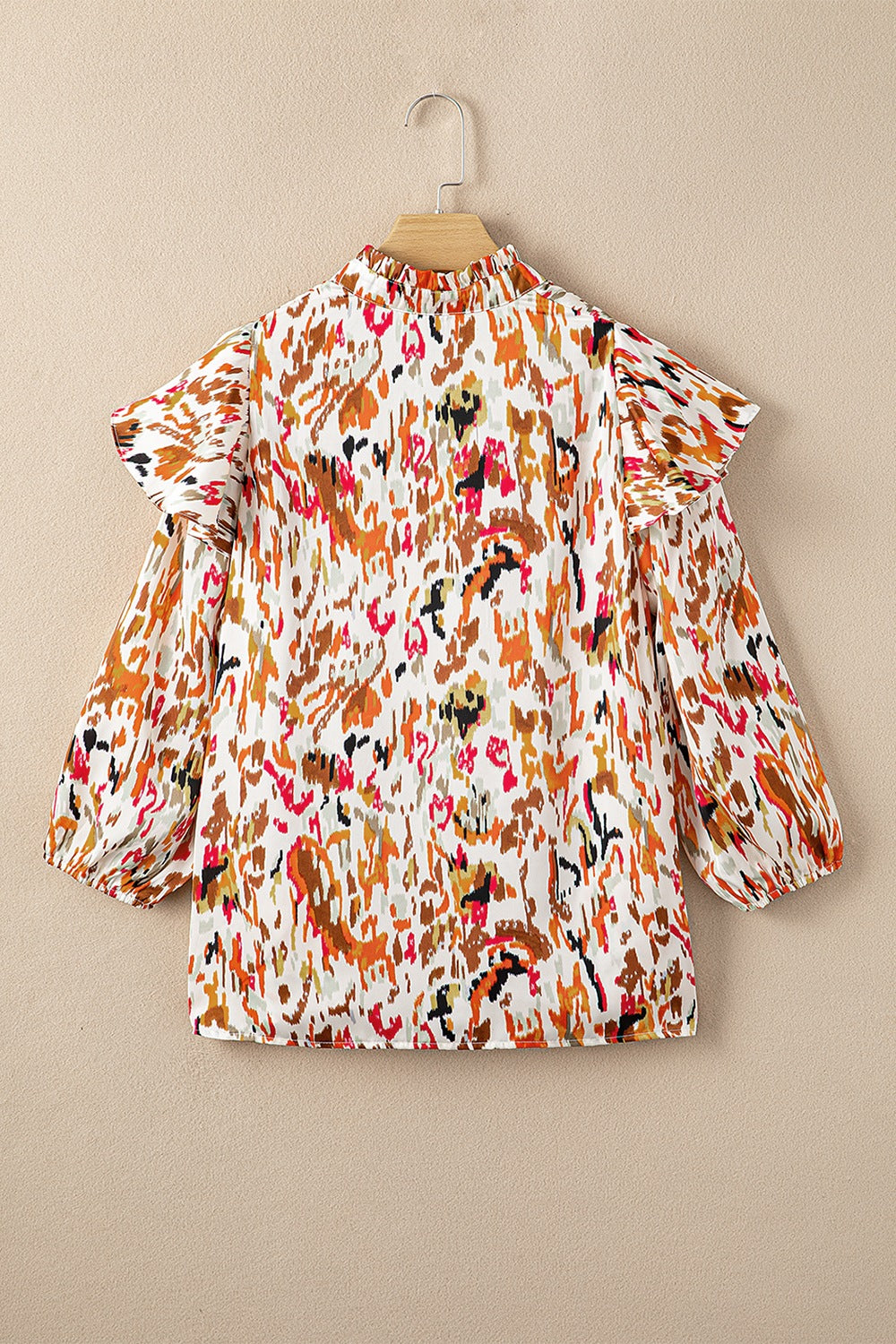 Blouse with abstract print, ruffled aura sleeves, and mock neck.