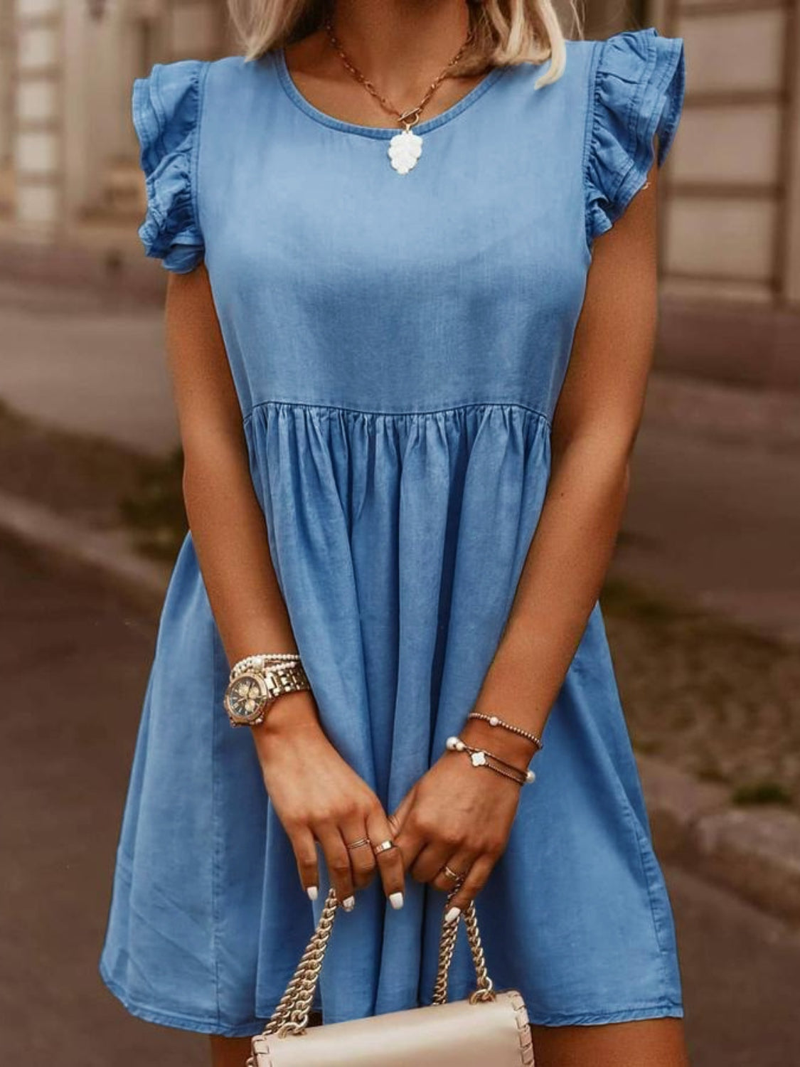 Light blue denim babydoll dress with ruffled sleeves and tiered skirt.