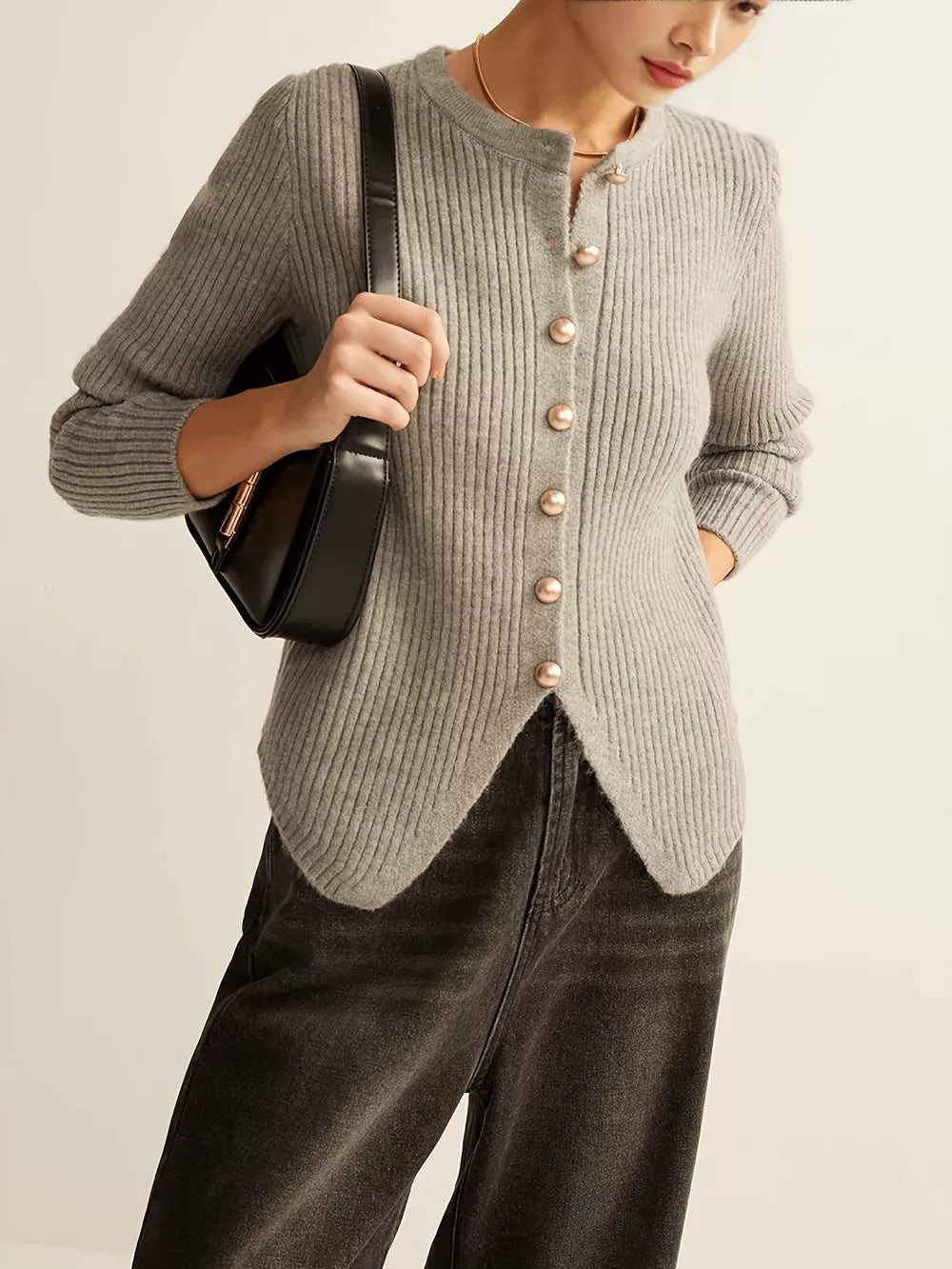 Grey ribbed knit cardigan with crew neck and gold button accents, featuring an asymmetrical hem.
