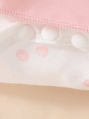 Pink baby dress with white polka dots and snap closures