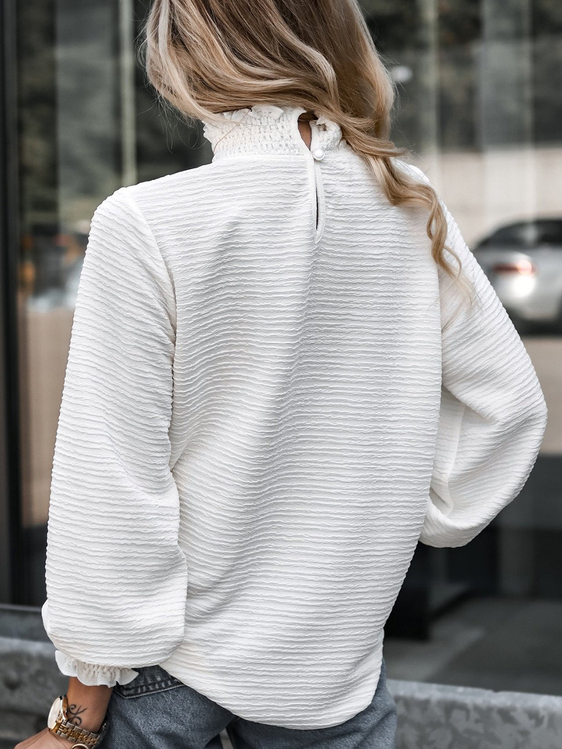 White textured blouse with smocked mock neck and puff sleeves.