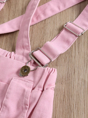 Pink denim baby overalls with adjustable straps and silver hardware detail.