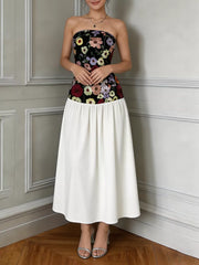 Strapless maxi dress with black floral embroidered bodice and white skirt.