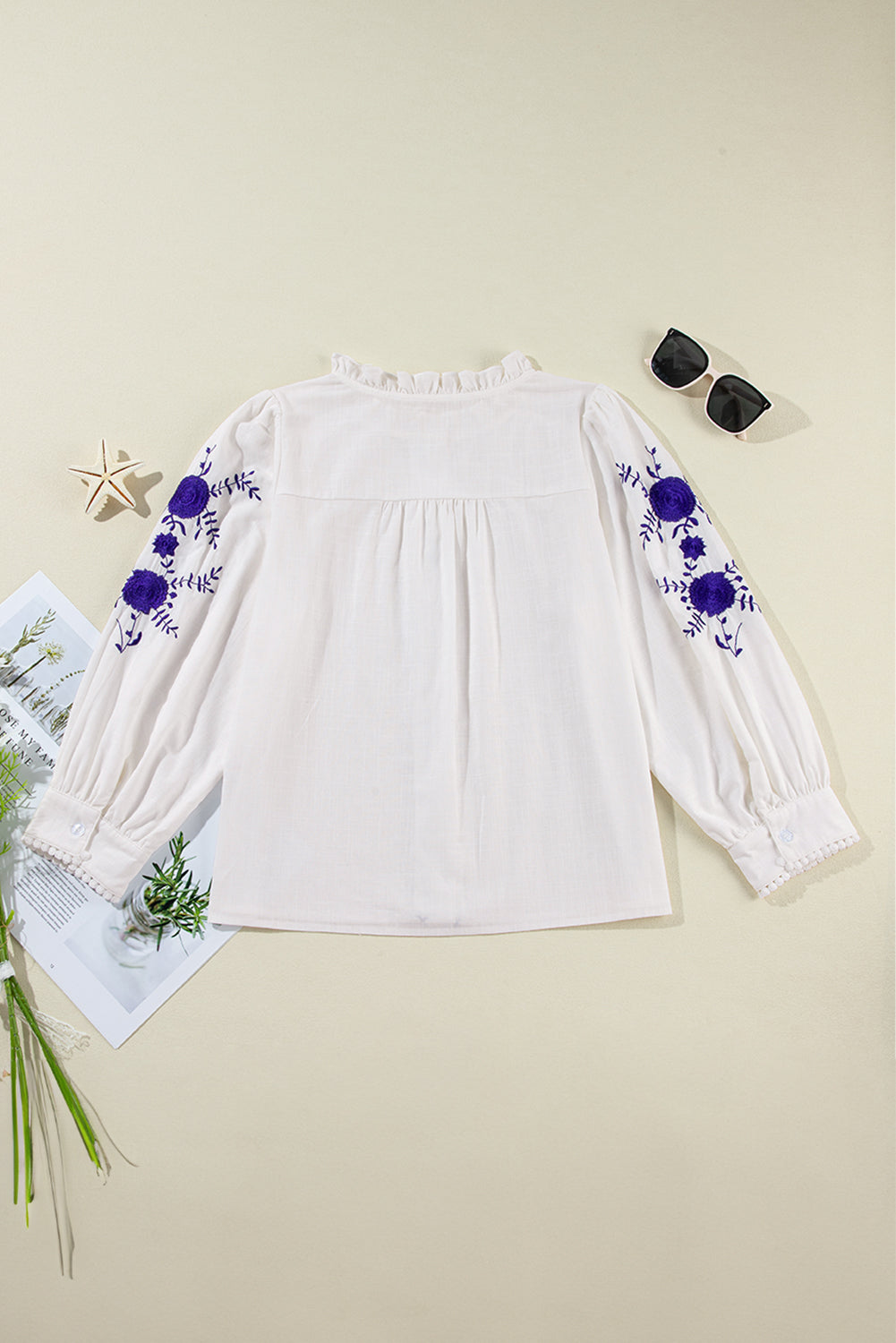 White embroidered blouse with ruffled neckline, long sleeves, and scalloped trim.