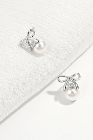 Silver bow pearl drop earrings with a classic pearl and delicate bow detail.