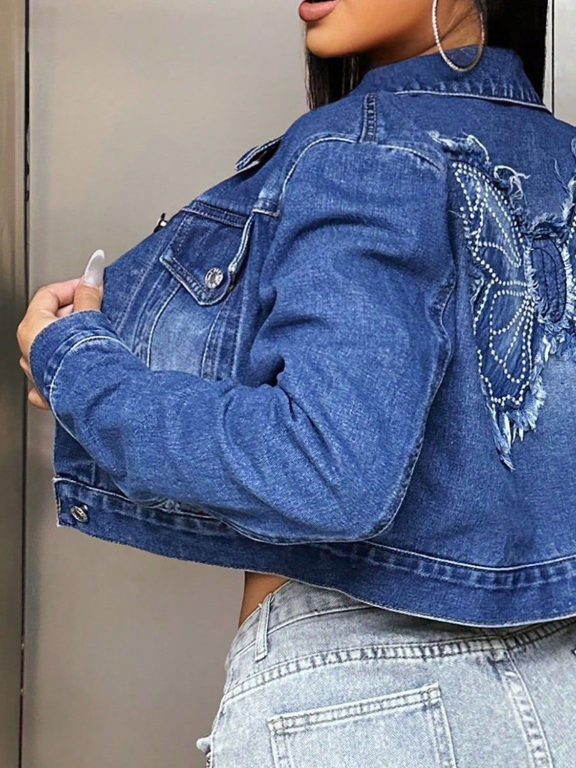 Embroidered butterfly denim crop trucker jacket in medium wash cotton with distressed details.
