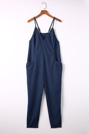 Navy jersey jumpsuit with V-neck, spaghetti straps, and slouch pockets.