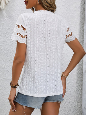 White eyelet blouse with scalloped short sleeves and textured fabric detail.