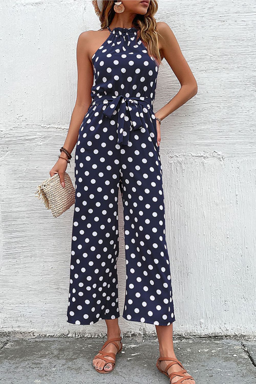Navy polka dot halter neck palazzo jumpsuit with tie waist and wide legs.
