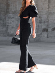 Black cotton blend jumpsuit with puff sleeves, V-neck, cutout waist, and flared legs.