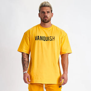 Oversized yellow graphic tee with black "VANQUISH" text, short sleeves, and crew neck.