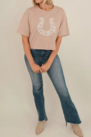 Beige cotton crew neck tee with horseshoe lace and pearl accent.