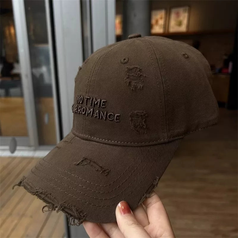 Brown distressed cotton baseball cap with embroidered text and frayed details.