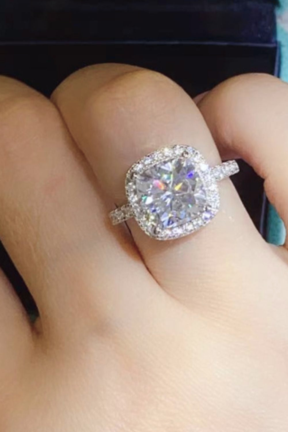 White gold cushion-cut halo engagement ring with a large center stone.