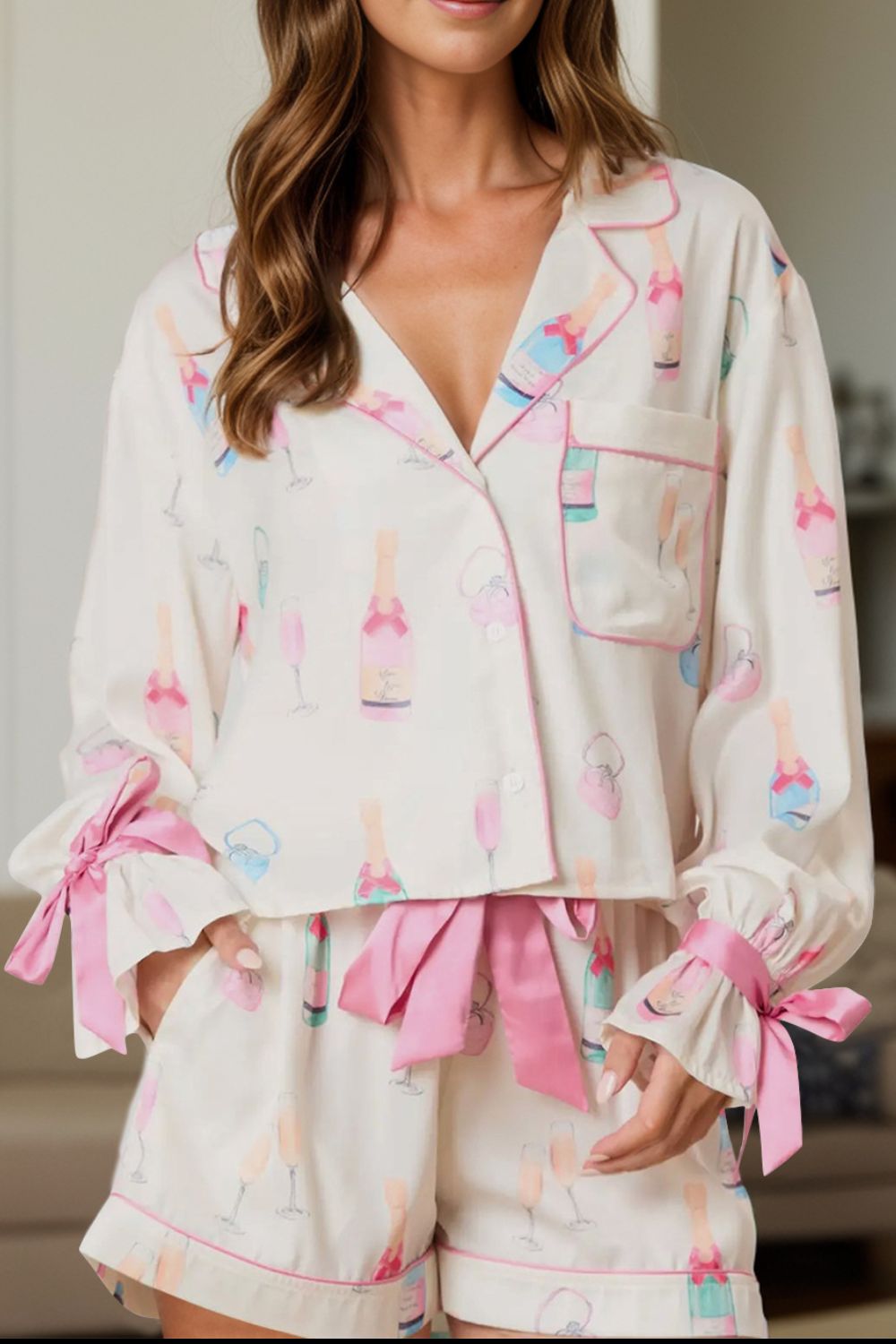 White silk pajama set with champagne print, collar, and pink bows on sleeves and shorts.