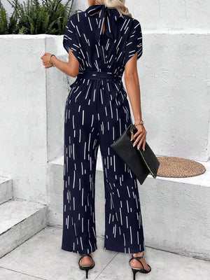 Navy wide-leg jumpsuit with raindrop print, belted waist, and bow-back detail.