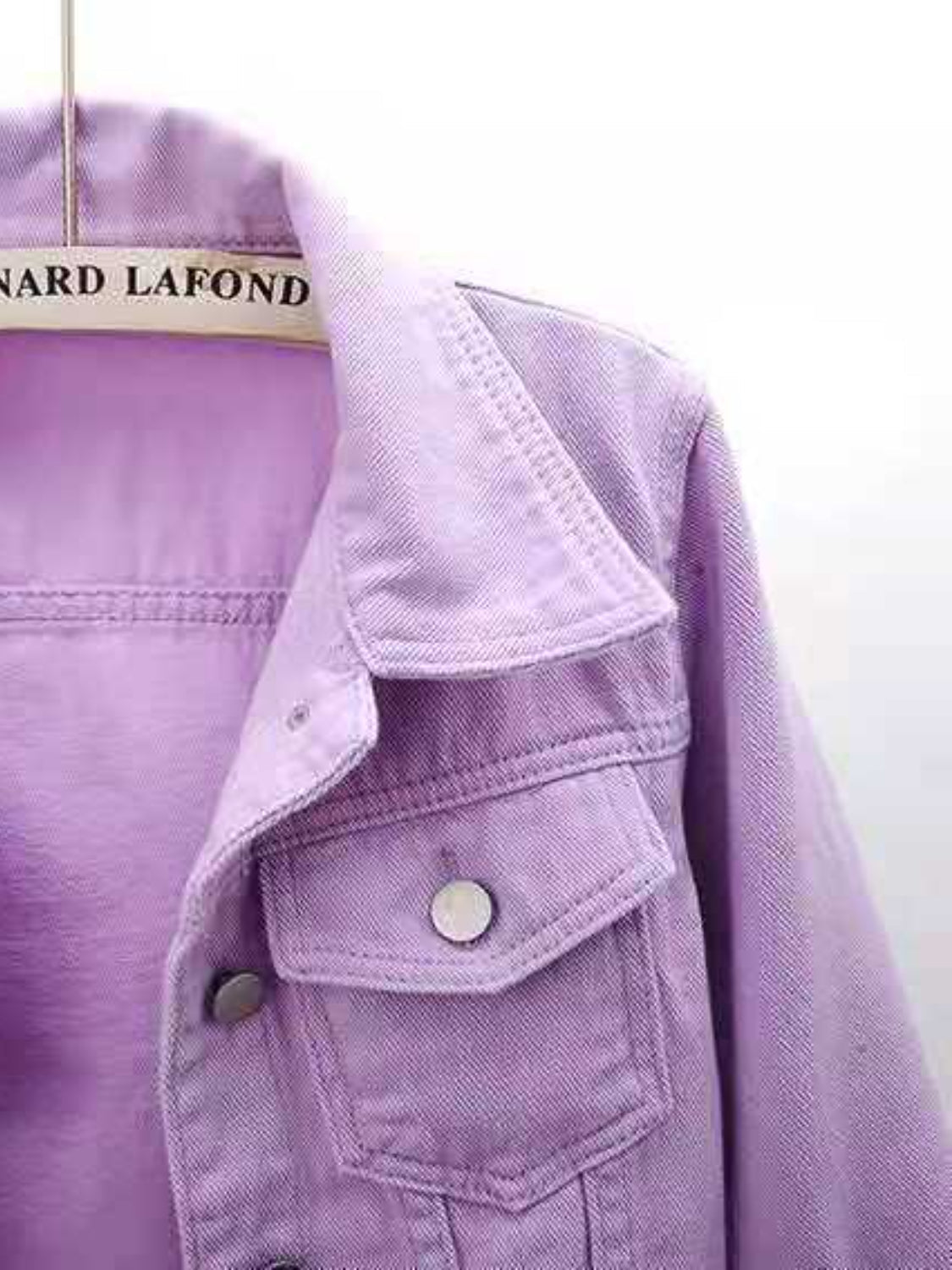 Lavender denim trucker jacket with button-flap chest pockets and collar detail.