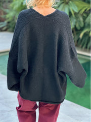 Black oversized knit cardigan with V-neck and relaxed fit, showing back detail.