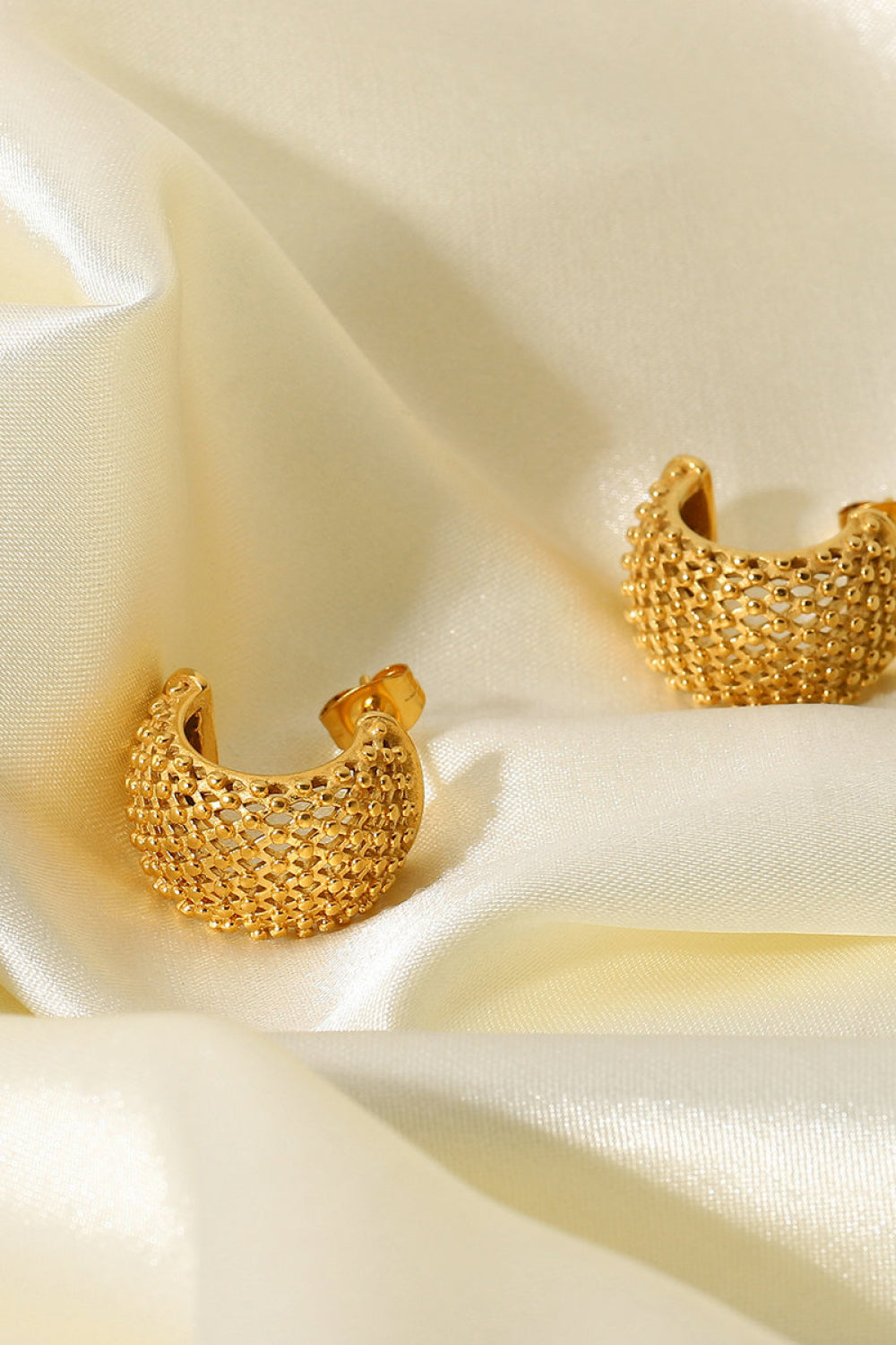Textured gold crescent earrings with a beaded pattern.