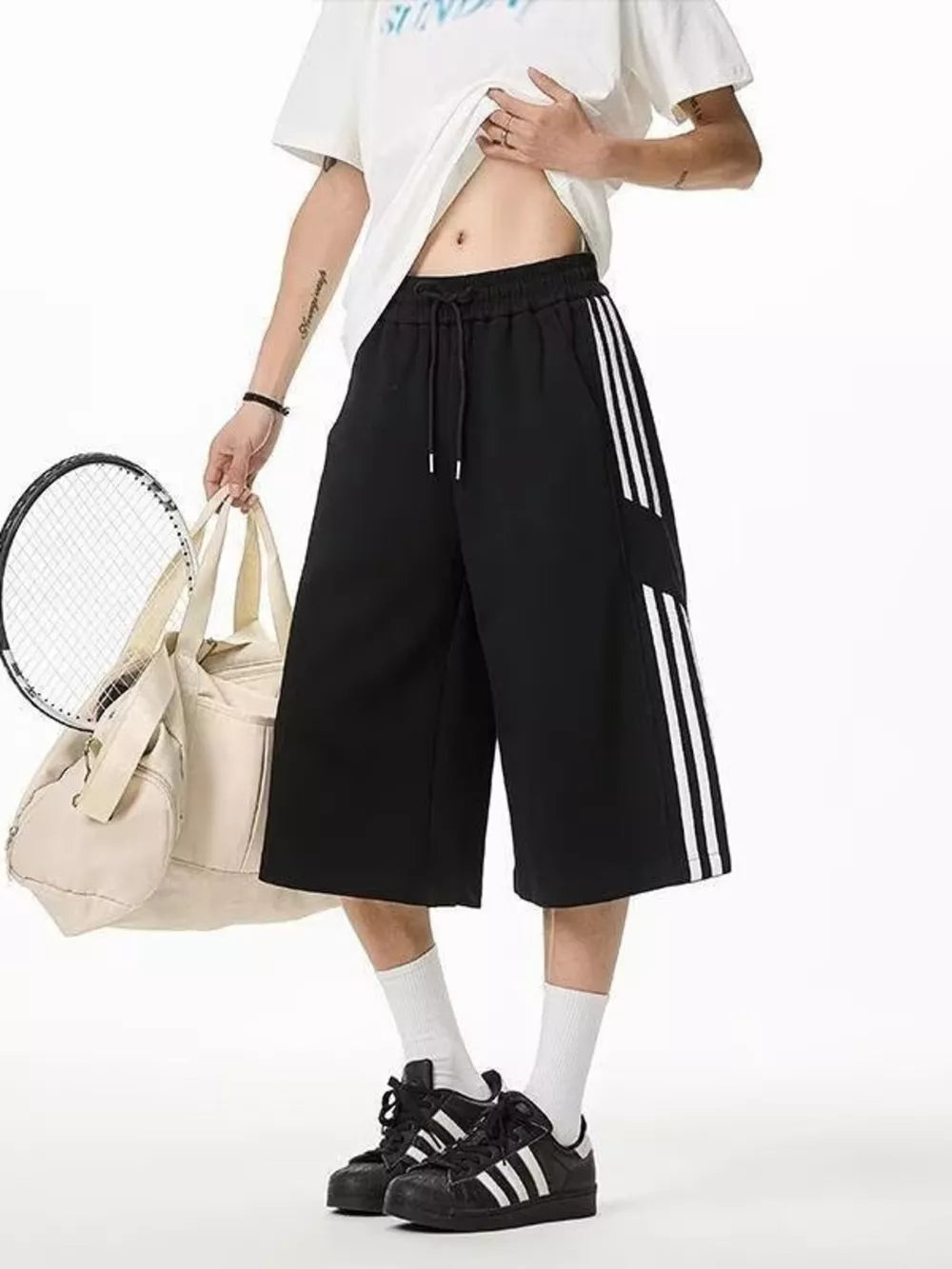 Black cropped sweatpants with white side stripes and drawstring waist.
