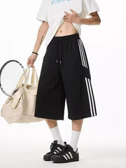 Black cropped sweatpants with white side stripes and drawstring waist.