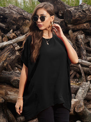 Black draped asymmetrical sleeve blouse with a relaxed fit, styled with jewelry.