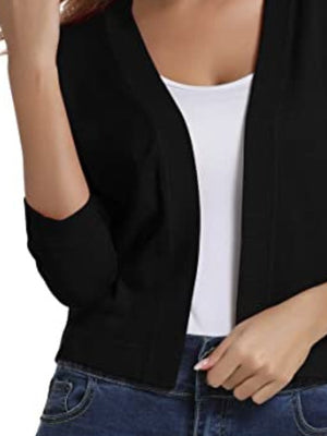 Black cropped knit cardigan with elbow sleeves and open front, worn over a white tank top.