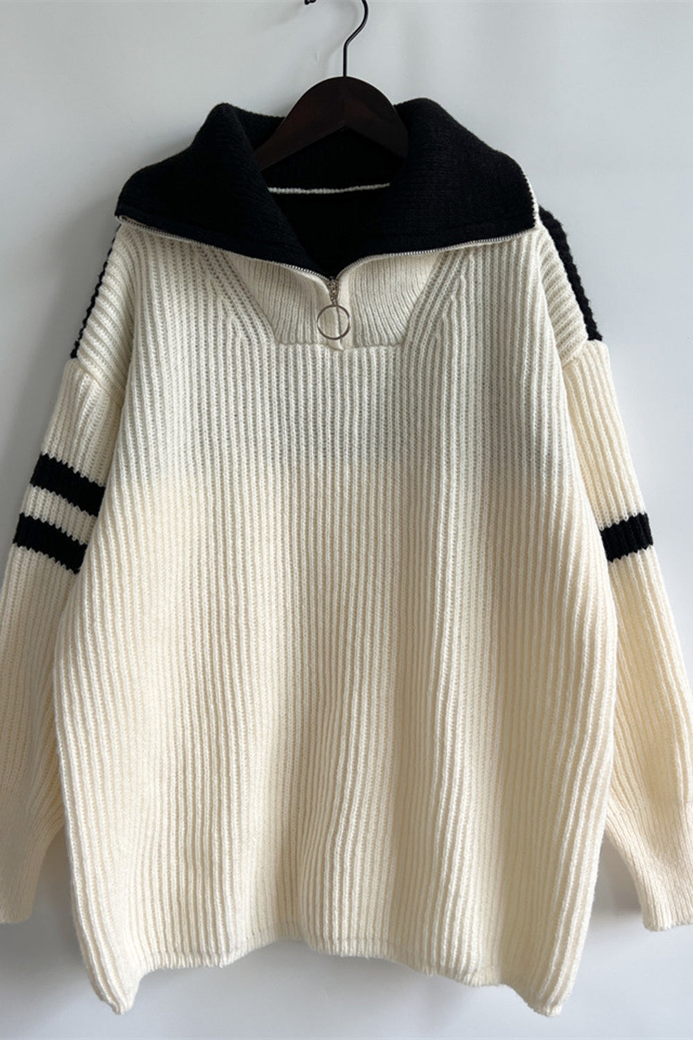 Cream ribbed knit quarter-zip sweater with black collar and sleeve stripes.