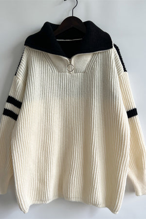 Cream ribbed knit quarter-zip sweater with black collar and sleeve stripes.