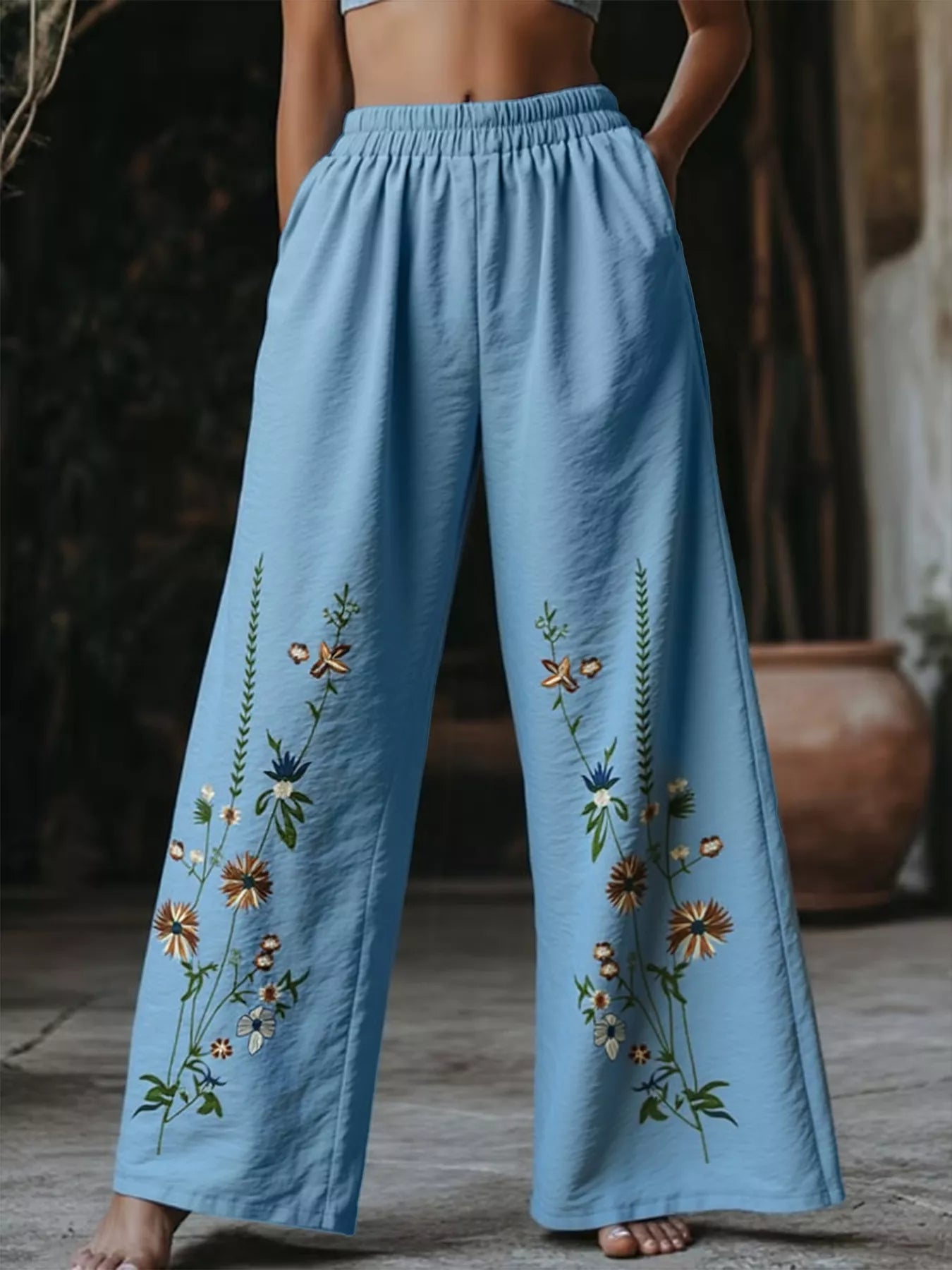 Sky blue wide-leg trousers with embroidered floral details and elastic waist.