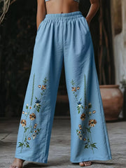 Sky blue wide-leg trousers with embroidered floral details and elastic waist.