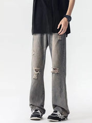 Men's grey loose fit jeans with distressed details and rips.