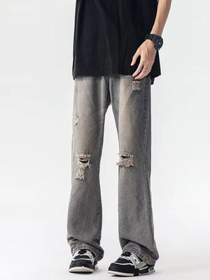 Men's grey loose fit jeans with distressed details and rips.