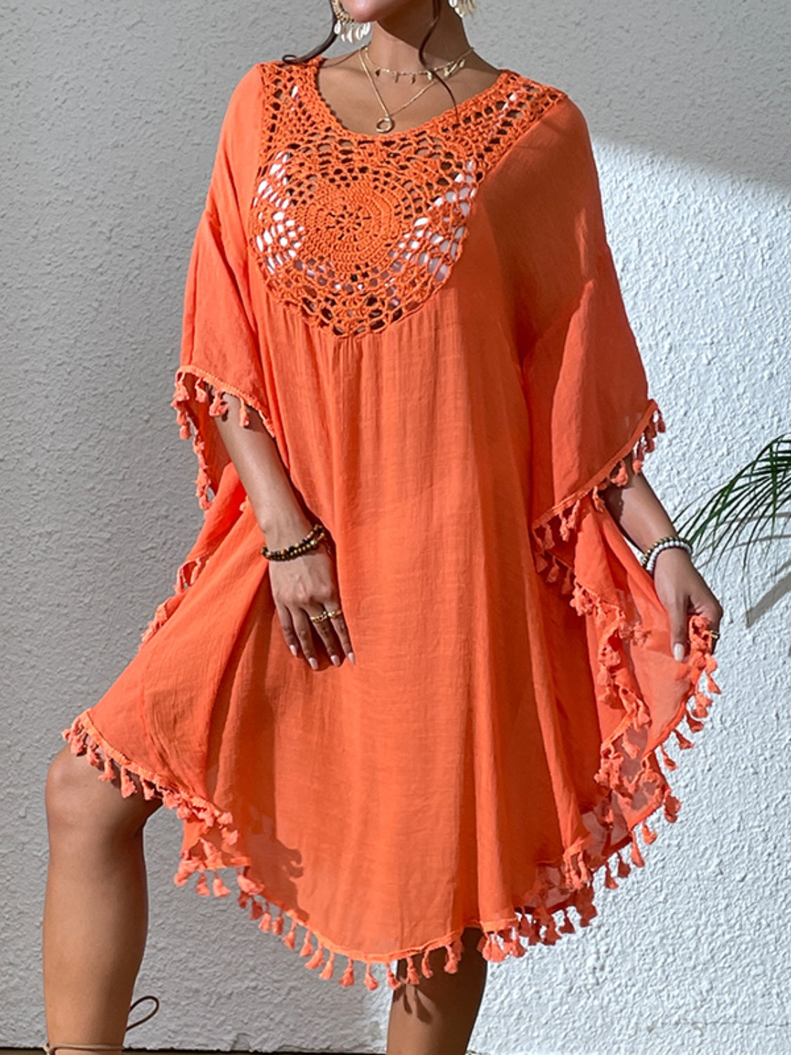 Orange kaftan dress with crochet yoke and tassel trim.