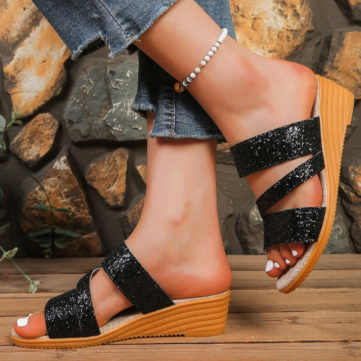 Black sequined wedge sandals with crisscross straps and a wooden wedge heel.