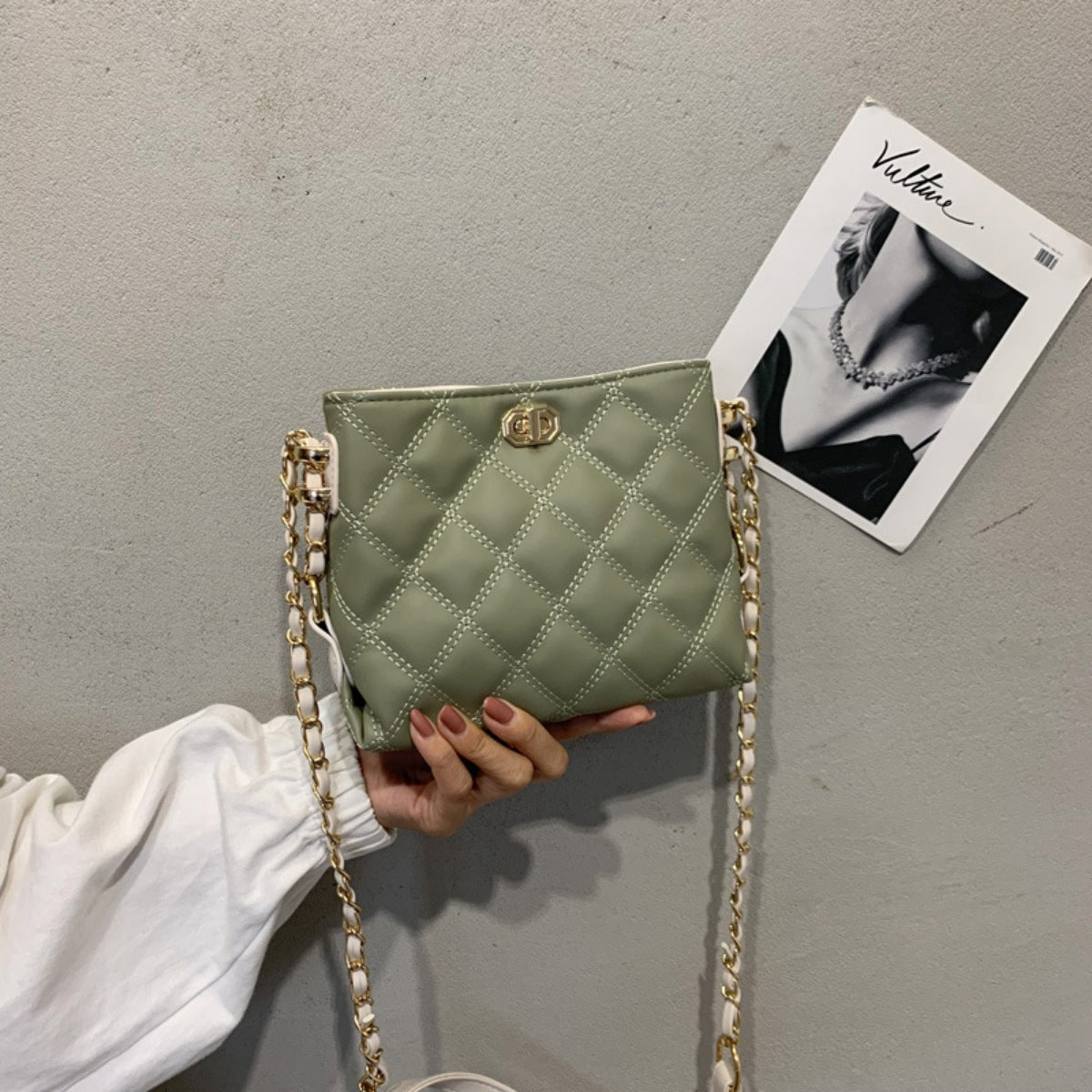 Green quilted crossbody bag with diamond pattern and gold chain strap.