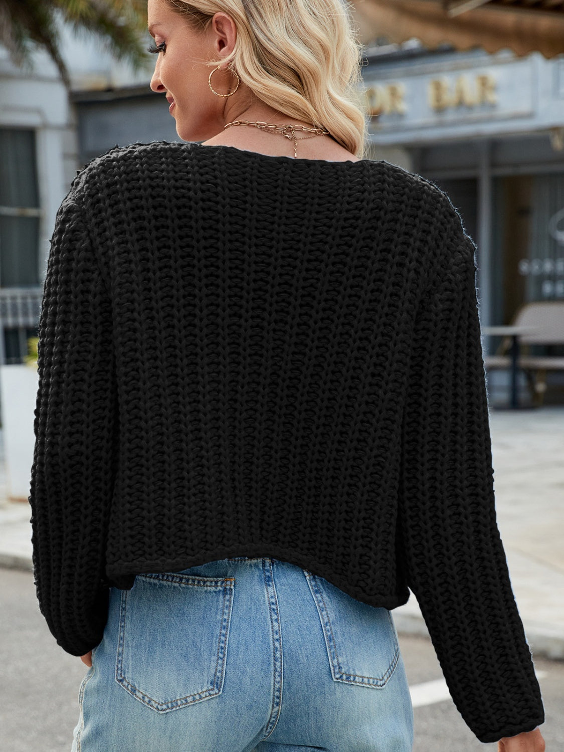 Black chunky knit acrylic cardigan with gold buttons, shown from the back.