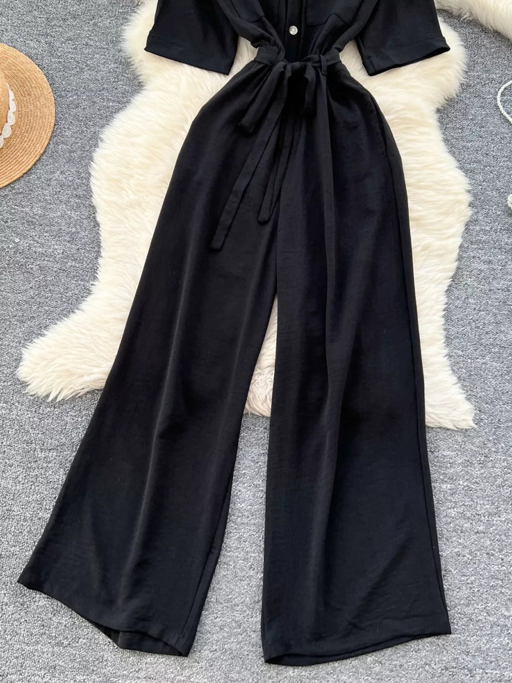 Black belted wide-leg maternity jumpsuit with button detail and tie waist.