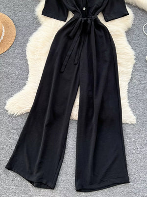 Black belted wide-leg maternity jumpsuit with button detail and tie waist.