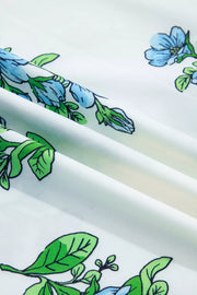 White polyester shirt with blue floral and green leaf print, showing fabric texture.