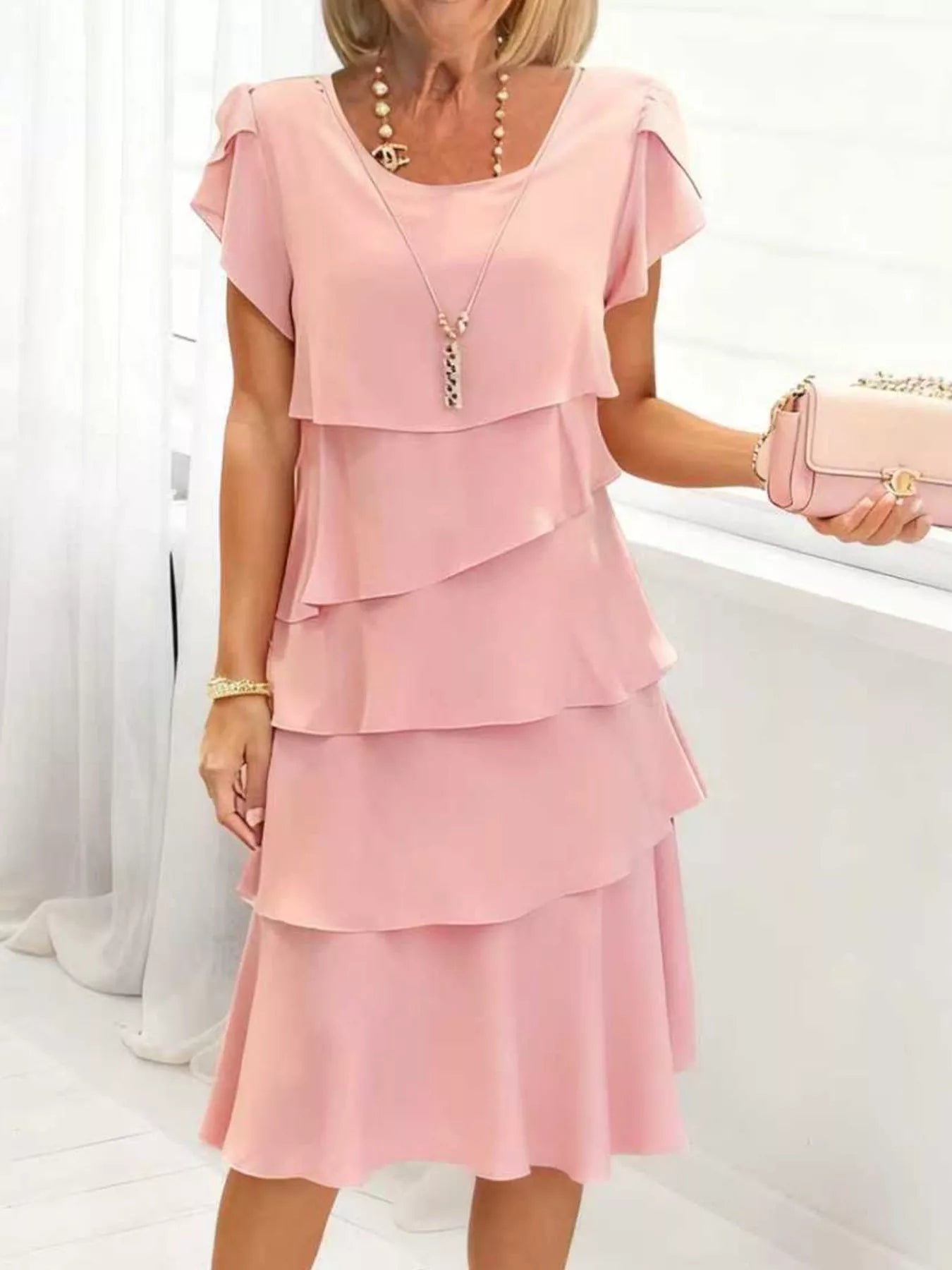 Blush pink tiered petal sleeve dress with ruffled layers and a scoop neckline.