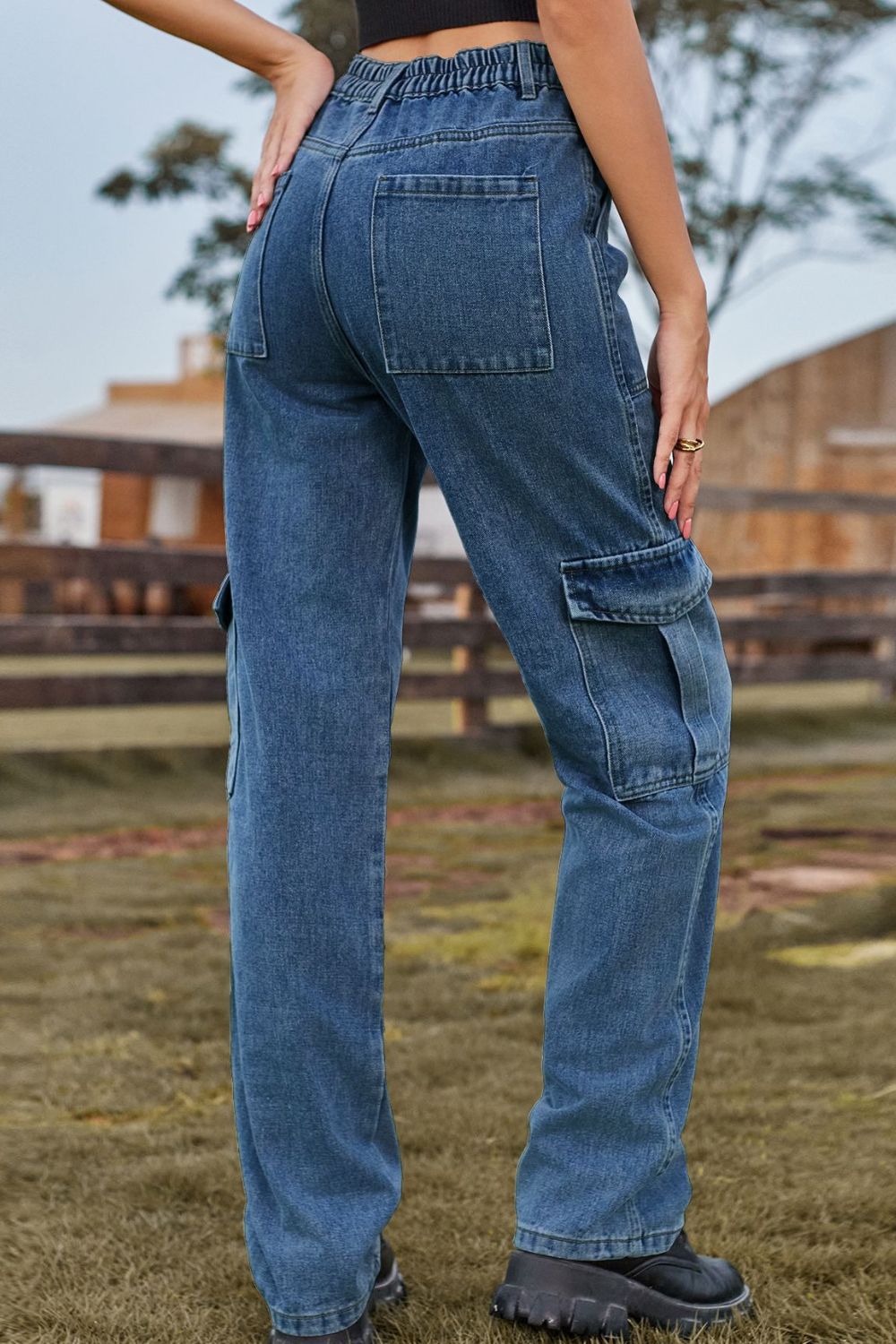 Medium wash denim cargo pants with utility pockets and elastic waistband.