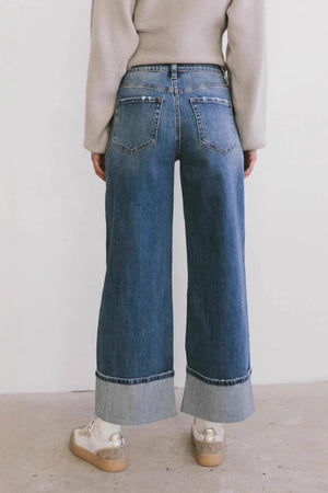 Wide-leg denim jeans in medium wash with contrast cuffs and distressed pockets.
