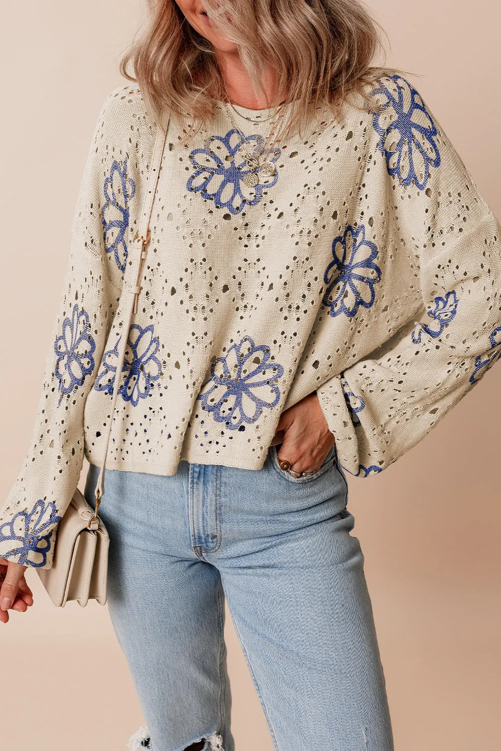 Beige floral embroidered eyelet knit pullover sweater with blue floral details.