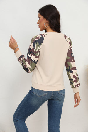Cream crewneck sweatshirt with camouflage raglan sleeves and ribbed cuffs.
