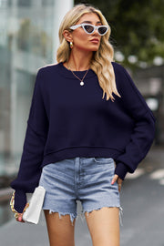 Dark blue ribbed knit batwing sweater with crewneck and cropped length.